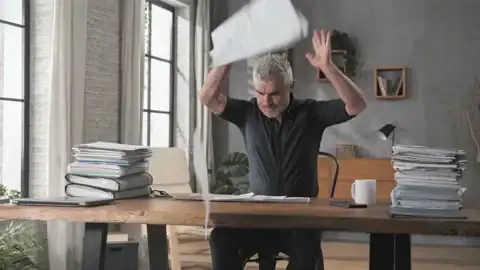 frustrated person holding TV bill with contract papers on table